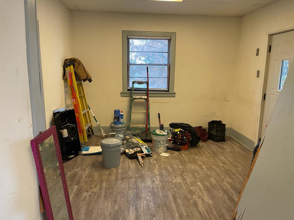 Empty rental living room left with ladders, paint buckets, tools and debris after tenant moved out in St. Louis