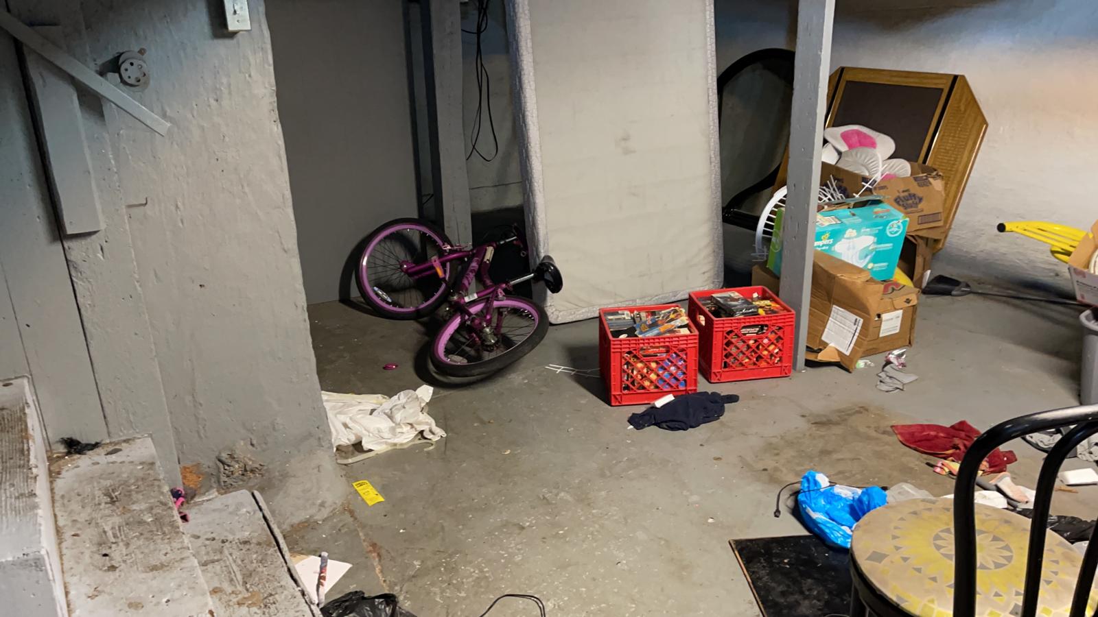 Cluttered basement with abandoned bike, milk crates, boxes and trash left by previous tenant in St. Louis rental