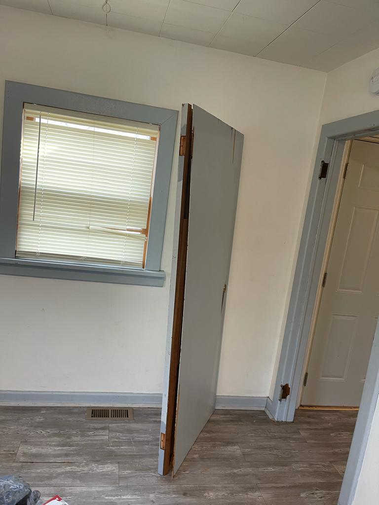 Bedroom with a detached door, scuffed walls and unfinished condition before cleanup in a St. Louis rental