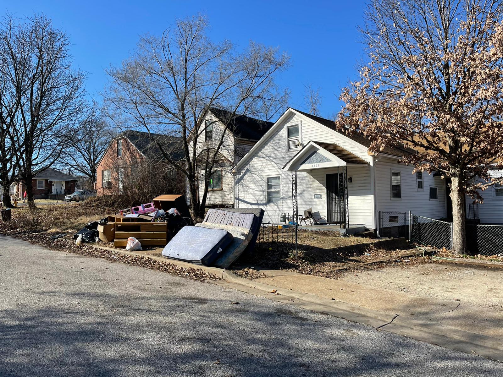 Rental home exterior with abandoned mattresses, furniture and trash piled at the curb after eviction in St. Louis